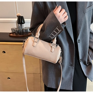 Detail of beige pleated cylinder handbag with silver hardware and adjustable strap