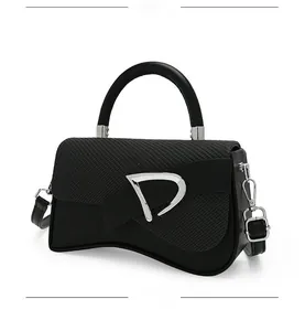 Detail of black crossbody box bag with silver D-buckle and woven leather texture