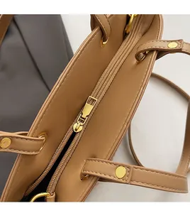 Detailed view of the brown tote bag featuring a smooth gold metal zipper and sturdy rivets
