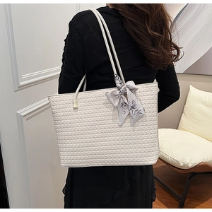 Detail of white woven tote bag with a decorative floral silk scarf on the shoulder strap