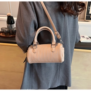 Detail of beige Boston bag with pleated texture, silver hardware and top handles