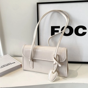 Minimalist creamy white faux leather baguette bag with detachable oval charm accessory