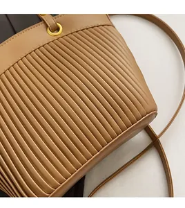 Detailed close-up of light brown tote bag featuring vertical pleated texture and gold hardware