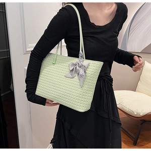 Close-up of light green woven tote bag texture with elegant floral silk scarf detail
