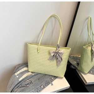 Detail of light green woven tote bag with floral silk scarf bow on denim jacket