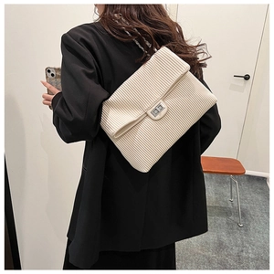 Detail of beige pleated tote bag with silver chain strap and metal swivel lock closure