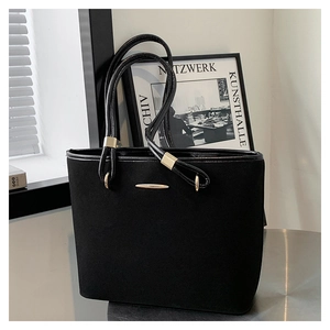 Close-up of black minimalist tote bag with matte texture and elegant gold hardware