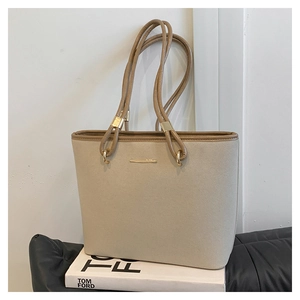 Close-up of beige tote bag with brown faux leather trim and gold hardware details
