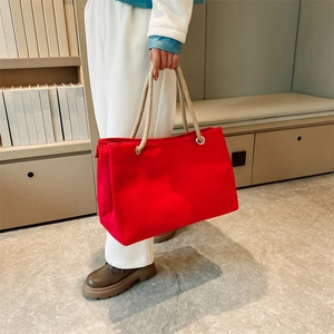 Large red canvas straw tote bag with brown hemp rope handles held in a stylish interior