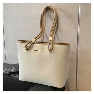 Detail of cream tote bag with khaki straps and elegant gold buckle on a soft fabric surface