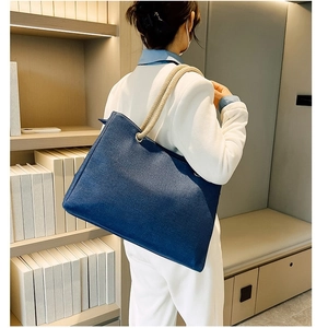 Large blue straw canvas tote bag with white rope handles shown in a lifestyle setting