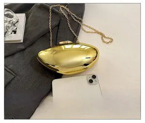 Detail showing high-polish gold hardshell evening bag with elegant acrylic chain strap