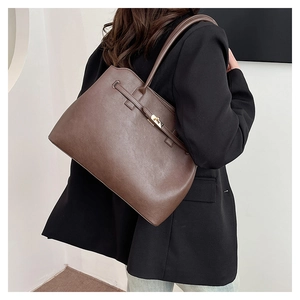 Detail view of large dark brown leather tote bag with metallic turn-lock and strap