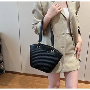 Detailed view of black pleated tote bag with golden metal rings and leather handle