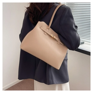 Chic beige tote bag with gold twist lock and shoulder strap shown on model for size
