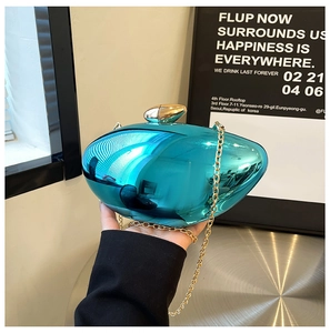 Detail showing shiny metallic blue shell clutch with golden capsule lock and thin chain strap
