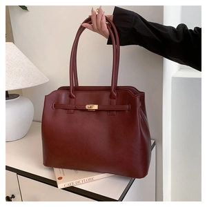 Detail of dark red faux leather handbag with classic metal twist lock and dual handles