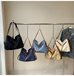Row of canvas tote bags in five colors hanging on a rack showing texture and straps