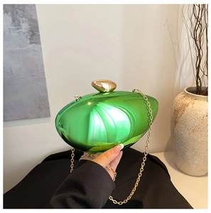 Detail of emerald green shell clutch with golden egg clasp and fine metal chain strap