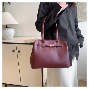 Detail of burgundy tote bag with gold buckle lock and premium synthetic leather texture