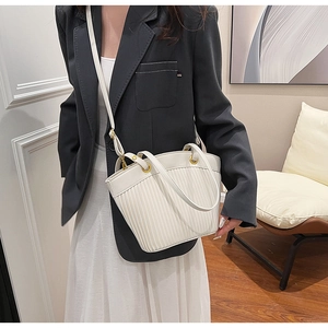 Close-up of a white pleated tote bag with matte gold hardware and adjustable strap