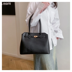 Classic black handbag with gold twist lock and strap detail, worn over the shoulder