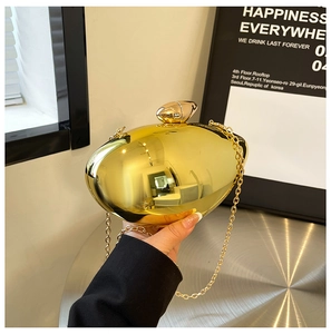 Macro detail of glossy gold metal evening clutch with pebble clasp and chain strap