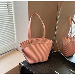 Detailed view of pink pleated handbag with soft texture and golden metal ring hardware