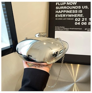 Detailed close-up of glossy mirror silver evening clutch bag with a metallic chain strap