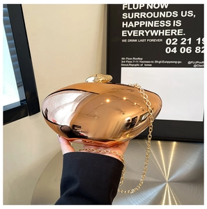 Detail of rose gold mirror finish heart-shaped clutch bag with delicate gold metal chain