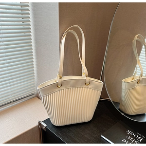 Close-up of pleated white vegan leather bag with elegant gold metal ring hardware detail