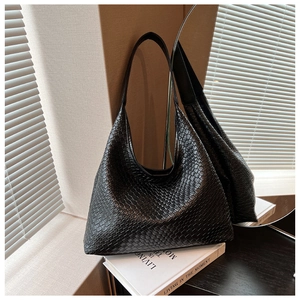 Macro shot of black woven leather texture and elegant shoulder strap on tote bag