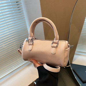 Pink minimalist cylindrical handbag with vertical embossed texture and adjustable shoulder strap