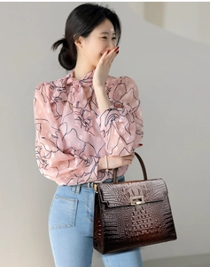 Detail view of pink floral chiffon blouse paired with brown crocodile pattern handbag