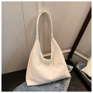 Detail of white woven leather texture on a minimalist tote bag against denim background