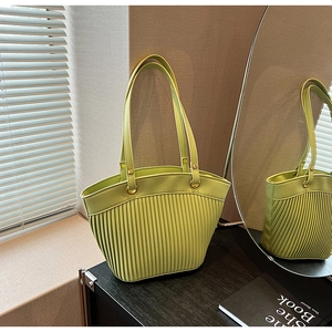 Detail of light green tote bag featuring unique pleated bottom design and gold metal rings