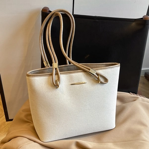 Elegant beige suede tote bag with brown straps and gold hardware on dark background
