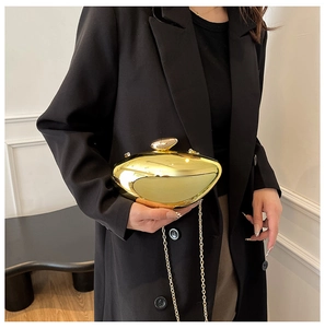 Polished gold pebble evening clutch bag with chain strap shown on a model