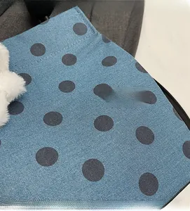 Close-up of blue polka dot canvas fabric with fluffy white pompom charm detail