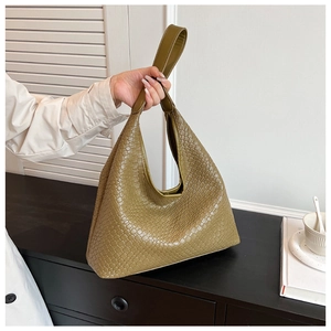 Detailed close-up of olive green woven leather tote bag texture and wide handle design