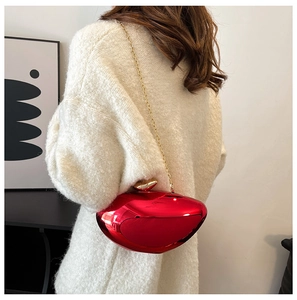 Close-up of red metallic clutch bag with golden leaf clasp and chain strap