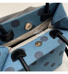 Detail of blue canvas bag with grey polka dots featuring a magnetic buckle closure