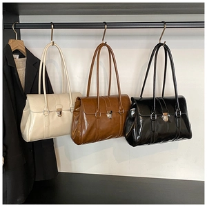 Three vintage leather shoulder bags in beige, brown, and black hanging on a clothing rack