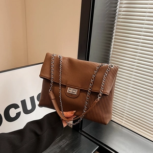 Brown corduroy tote bag with silver chain strap and metal lock closure in a chic lifestyle setting