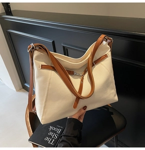 Detail of canvas tote bag with brown leather straps and silver metal hardware accents