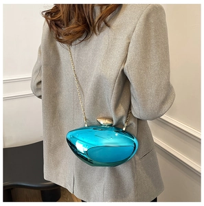 Detail of electric blue mirror finish evening clutch with gold chain on grey blazer