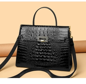 Detail of crocodile embossed leather texture and golden metal clasp on black Kelly bag
