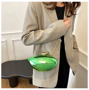 Detail of emerald green metallic clutch bag with gold chain strap on grey blazer