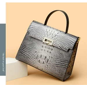 Close-up of grey crocodile embossed Kelly bag with gold metal lock and structured handle