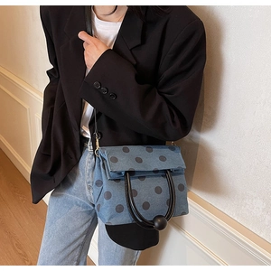 Polka dot denim handbag detail showing black rounded handle and spherical joint ornaments